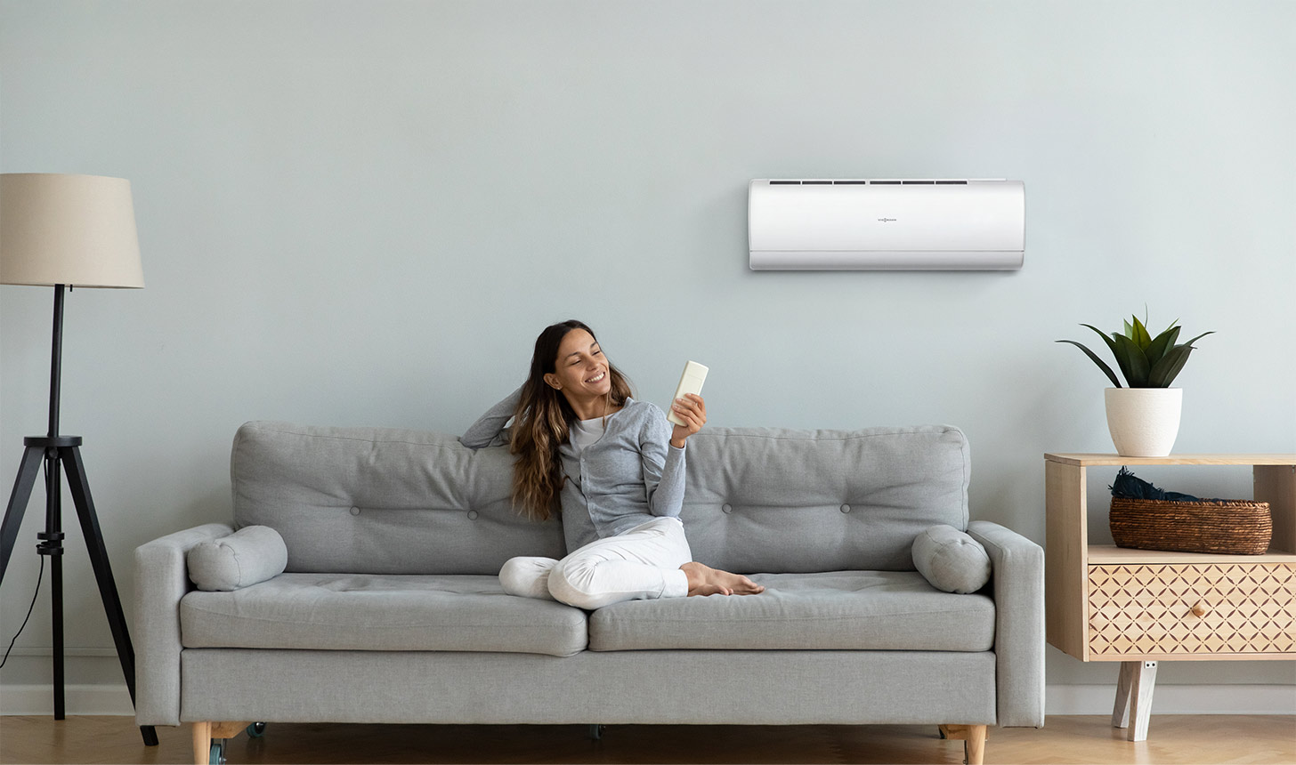 Frau auf Sofa, die Klimagerät bedient