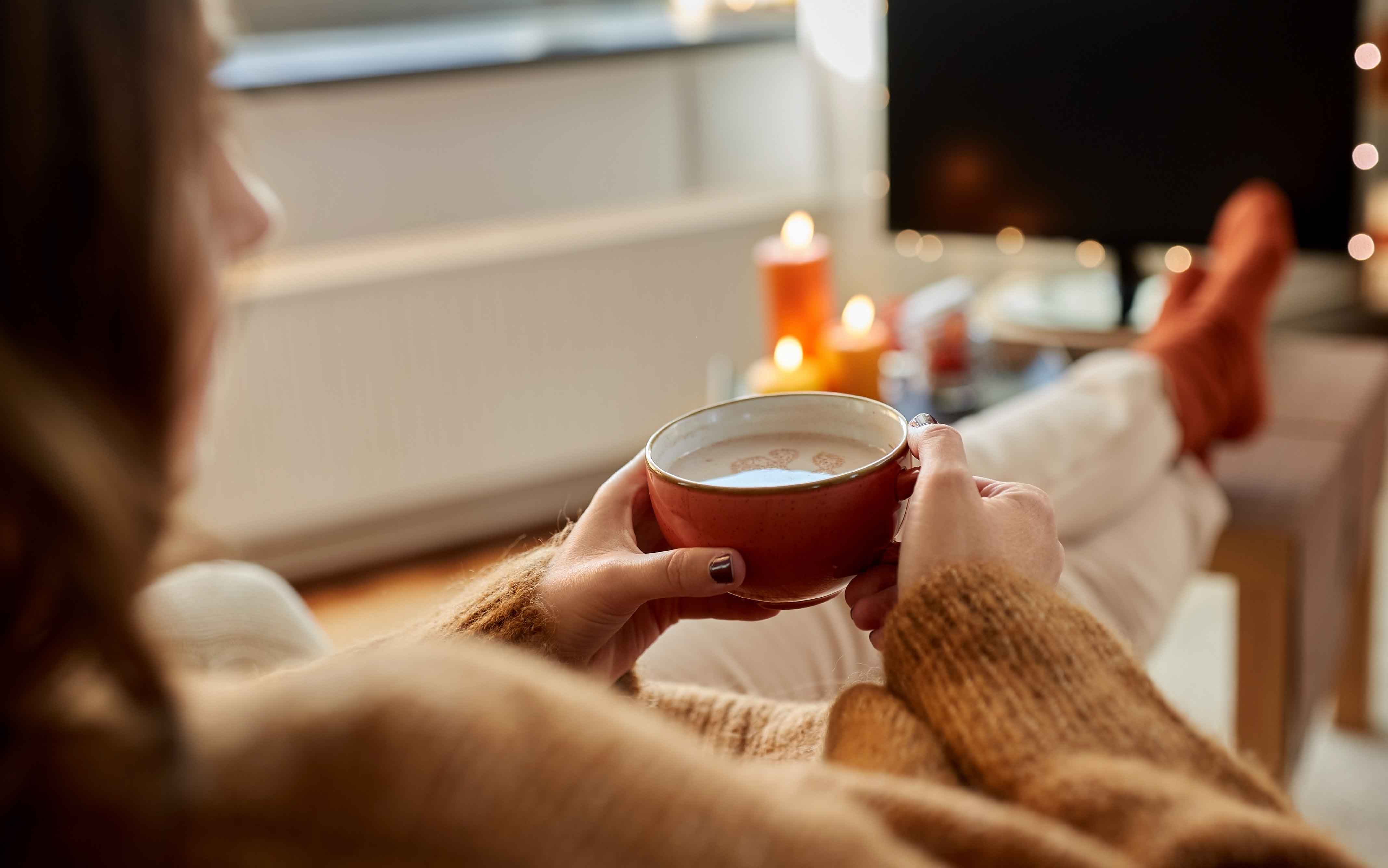 Frau macht es sich vor Flächenspeicherheizung gemütlich