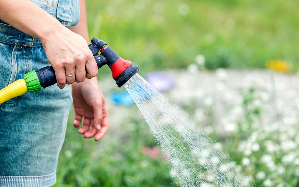 Frau bewässert Garten