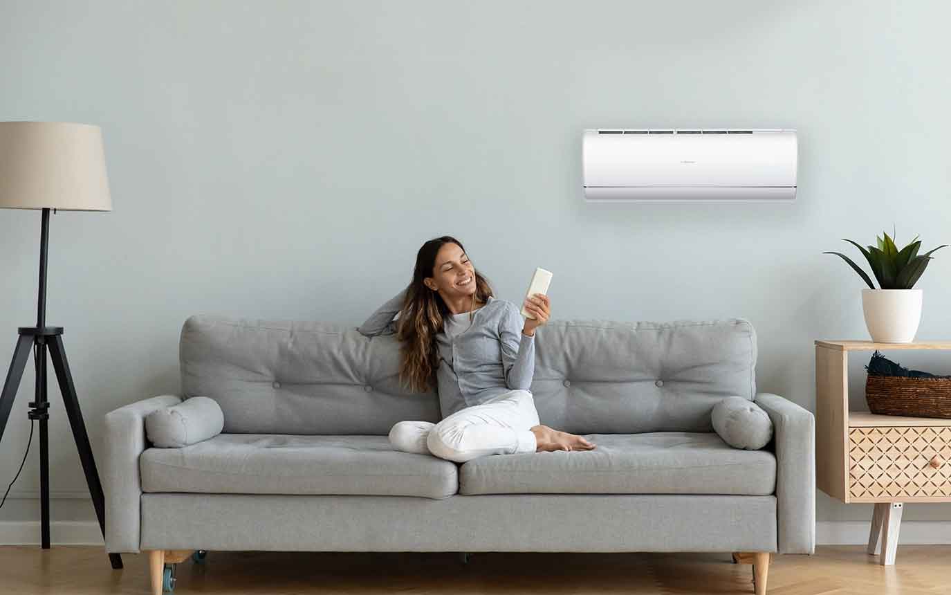 Frau auf Couch bedient Klimaanlage