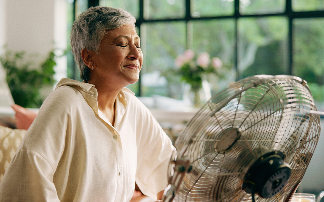 Frau kühlt sich am Ventilator ab