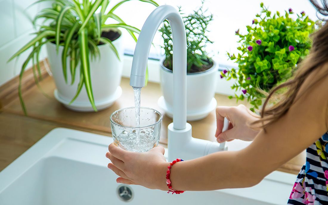 Mädchen füllt sich Leitungswasser ins Glas
