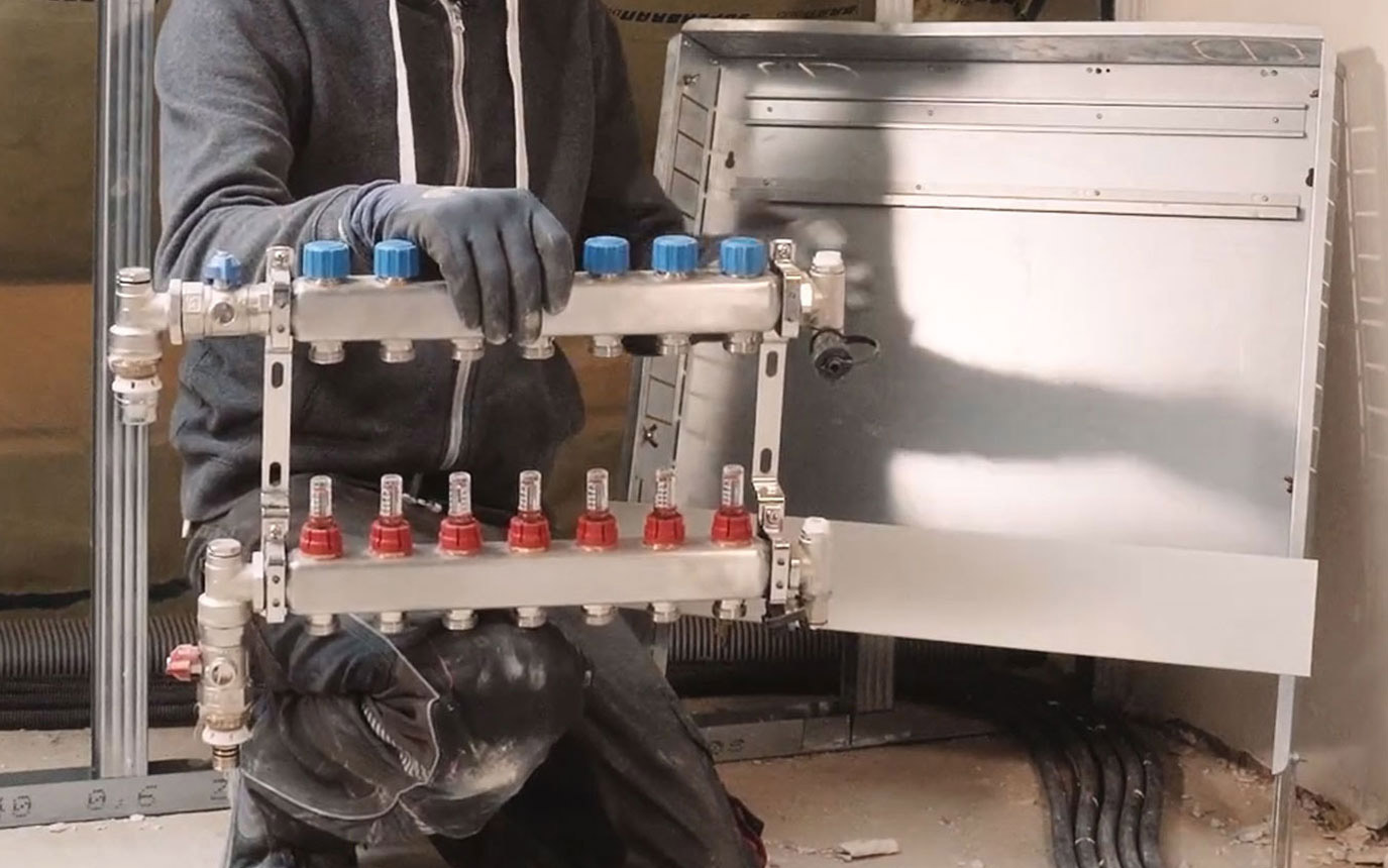 Mann hält Heizkreisverteiler