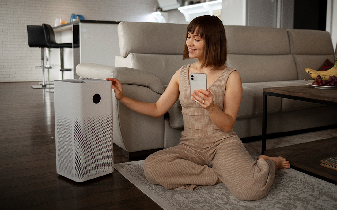 Frau sitzt neben Luftreiniger