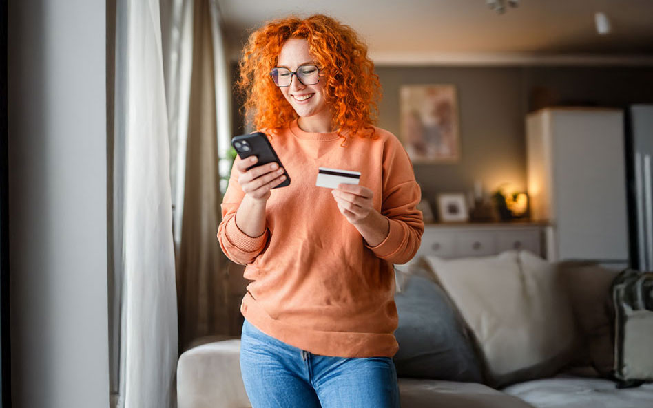 Frau gibt Daten von der Kreditkarte in ihr Handy ein