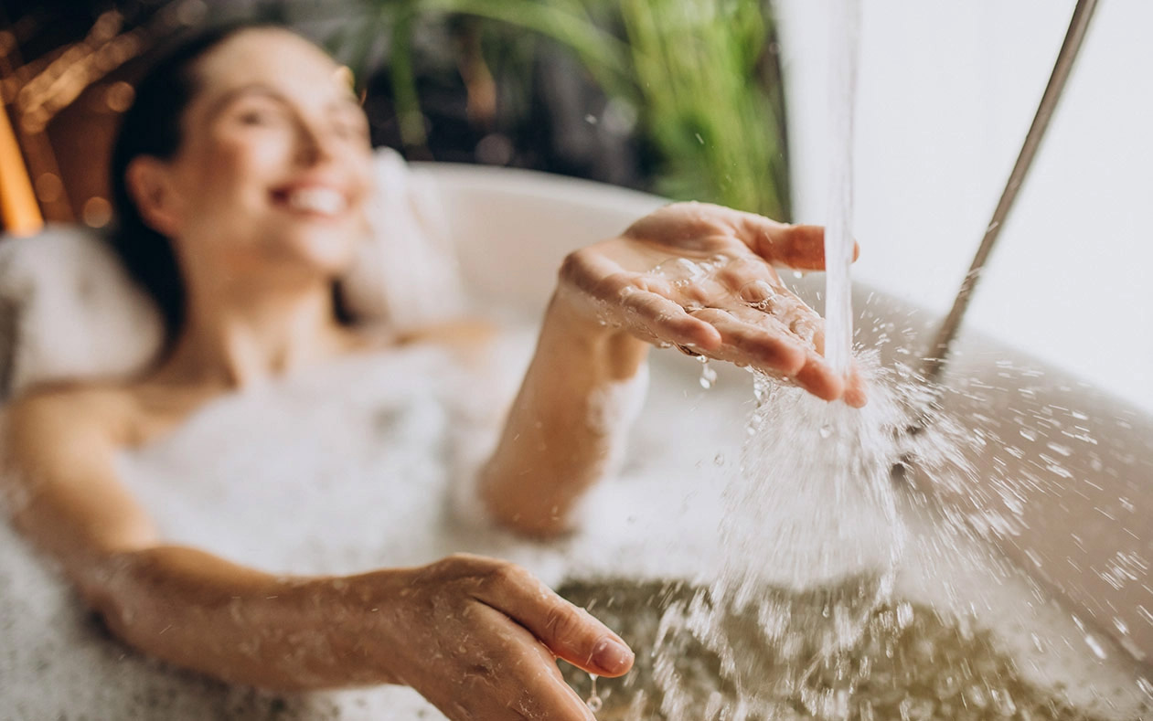 Frau liegt in Badewanne, wo Wasser eingelassen wird