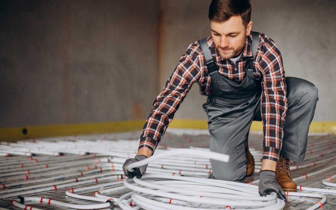 Mann verlegt Fußbodenheizungsrohre