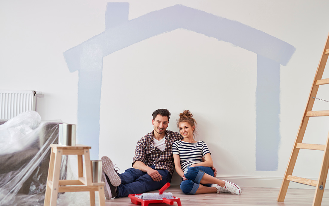 Pärchen sitzt unter einem an die Wand gemalten Haus