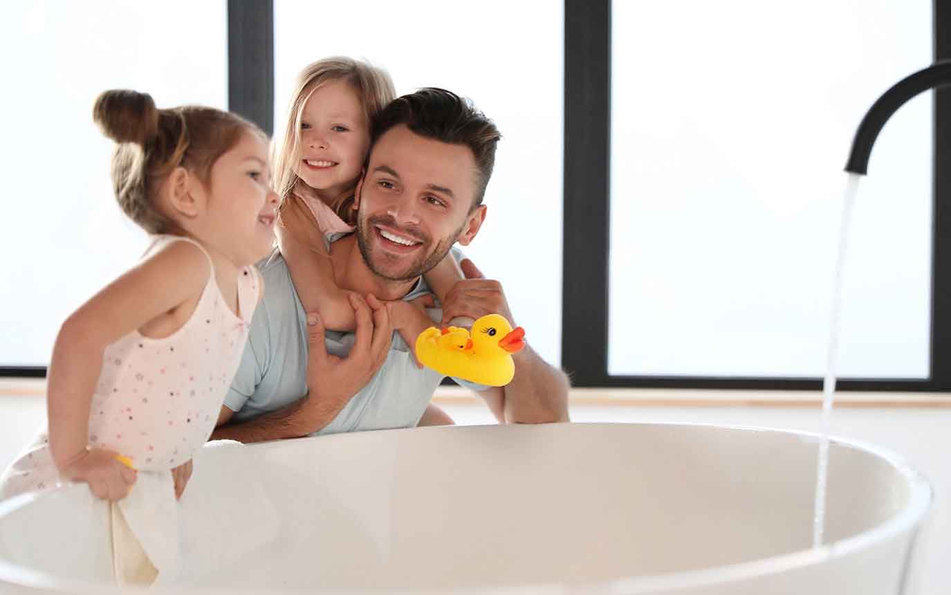 Familie beobachtet einlaufendes Wasser in Badewanne