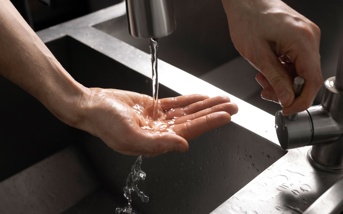 Hand mit Wasser aus dem Wasserhahn